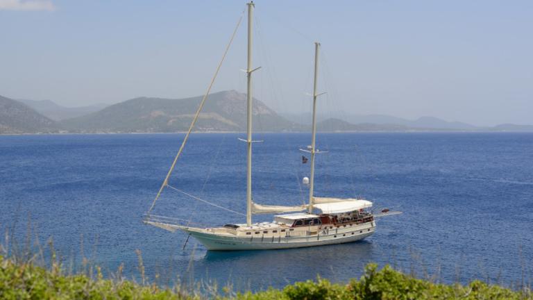 The luxury Cobra 3 gulet is docked at the shore, the mountains can be seen from behind